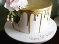 Gold white chocolate drip cake with roses, buds and leaves